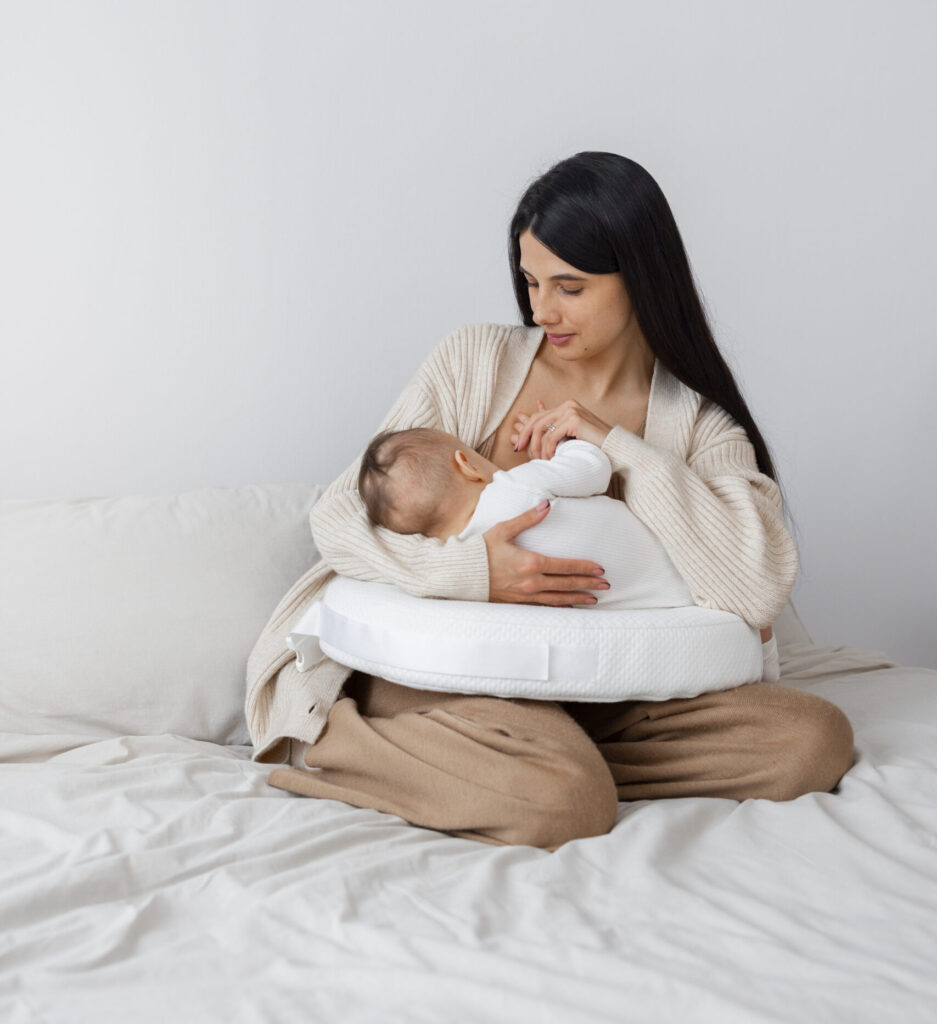 Mãe amamentando seu bebê em um ambiente acolhedor e tranquilo, utilizando um travesseiro de apoio para maior conforto durante a amamentação.